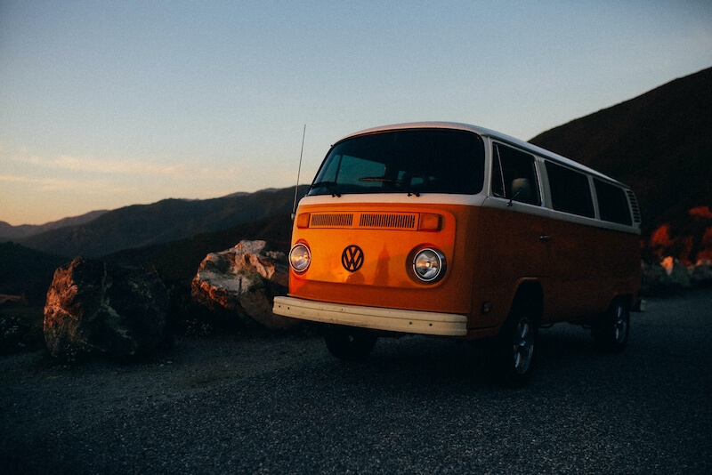 a vw van on top of a hill overlooking the sunset