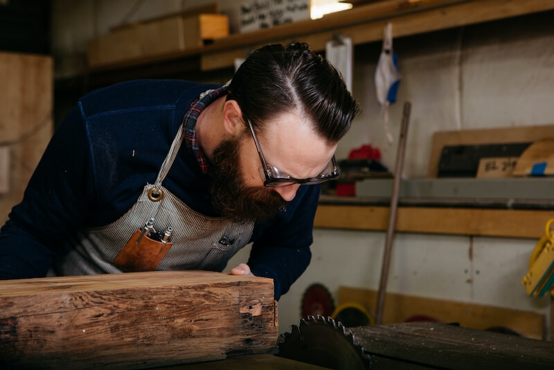 hombre cortando madera con una sierra de mesa