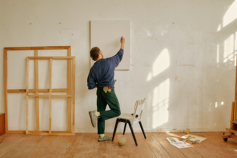 Ein Mann malt auf einer leeren Leinwand, die an einer Wand hängt