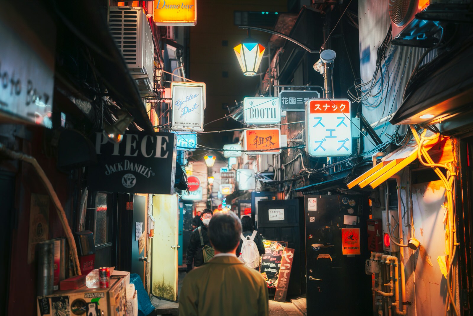 Ein Mann schaut in eine Gasse in Shinjuku, die mit Schildern in vielen verschiedenen Sprachen versehen ist.